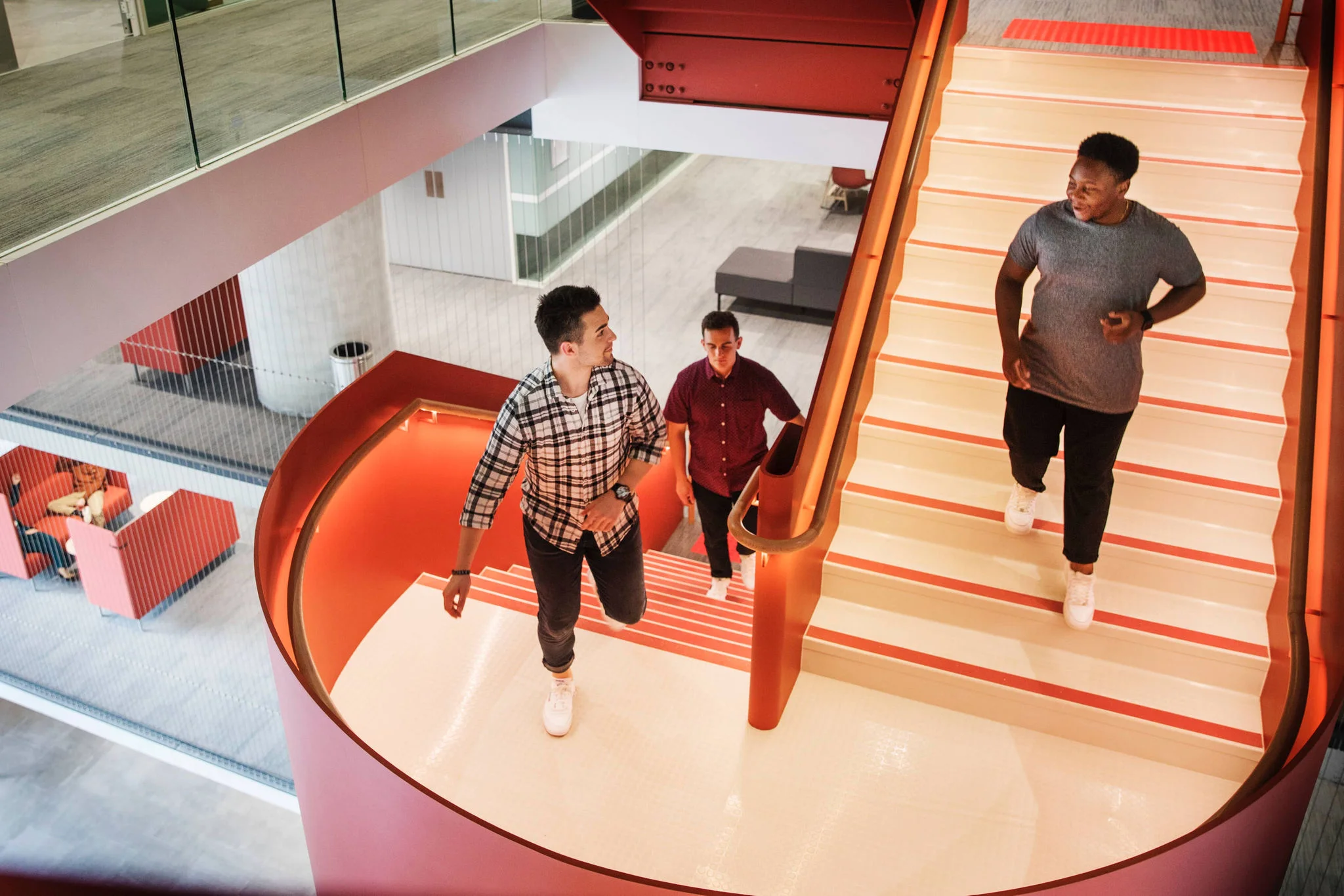 Three people walking on modern red staircase