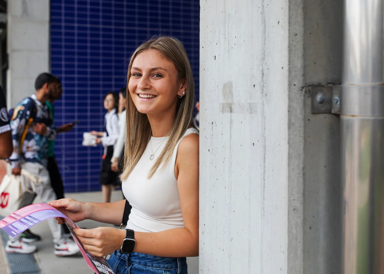 Young woman holding map near urban blue wall
