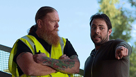 Two men. One with arms folded the other pointing