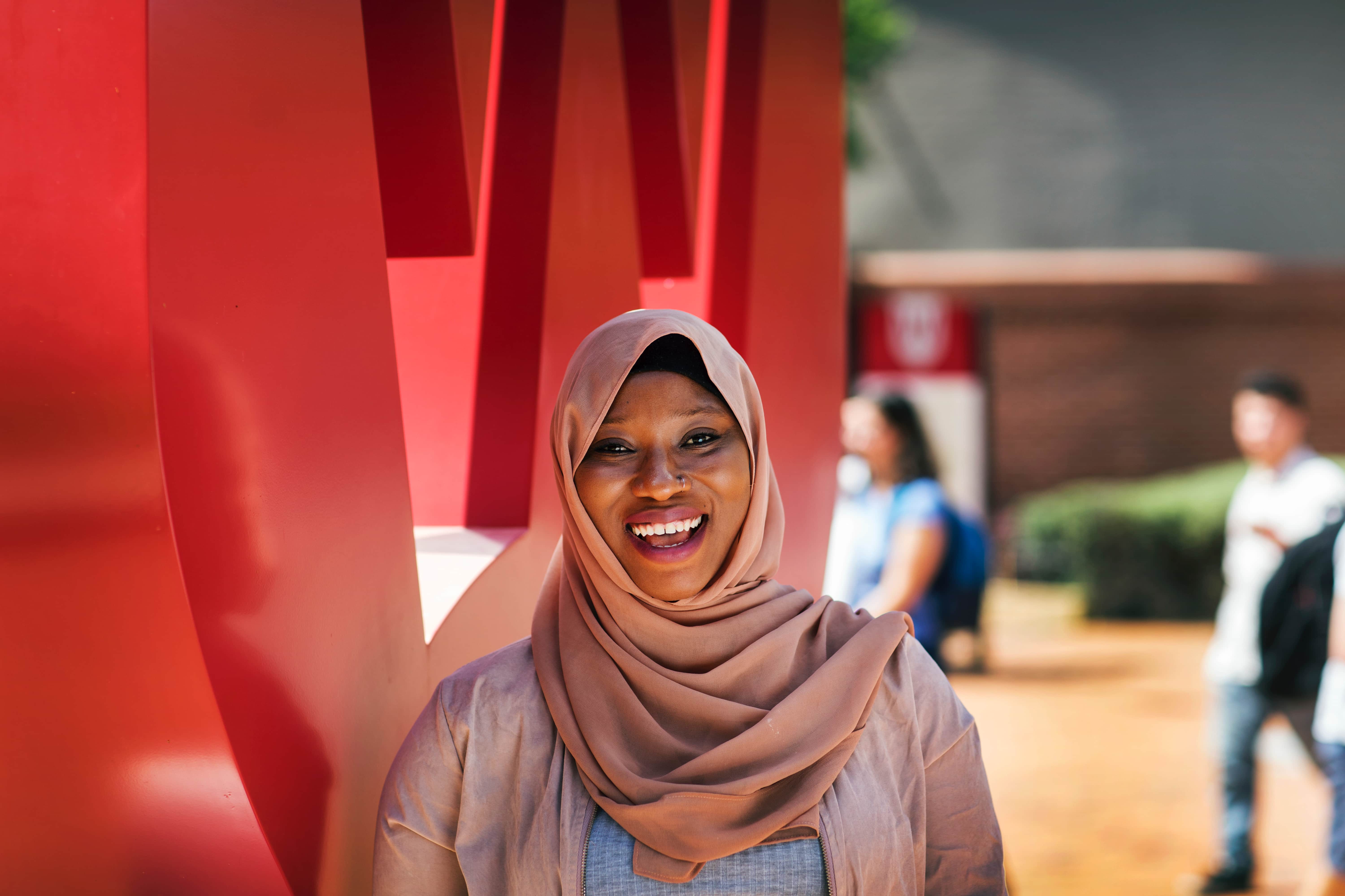 Person in hijab standing by large red structure outdoors