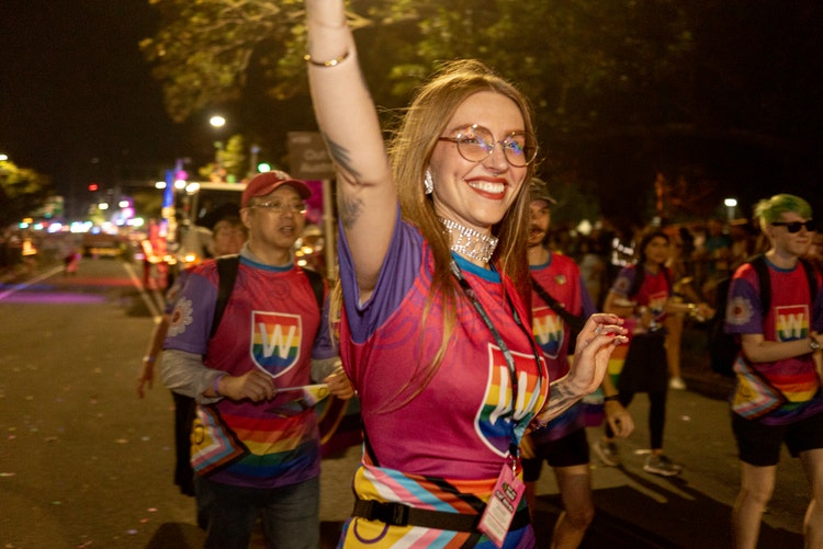 WSU Mardi Gras participants marching in the parade with one woman smiling and raising her arm in celebration